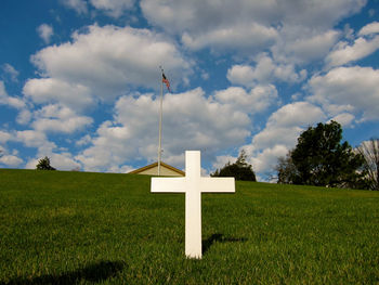 Road sign on field against sky