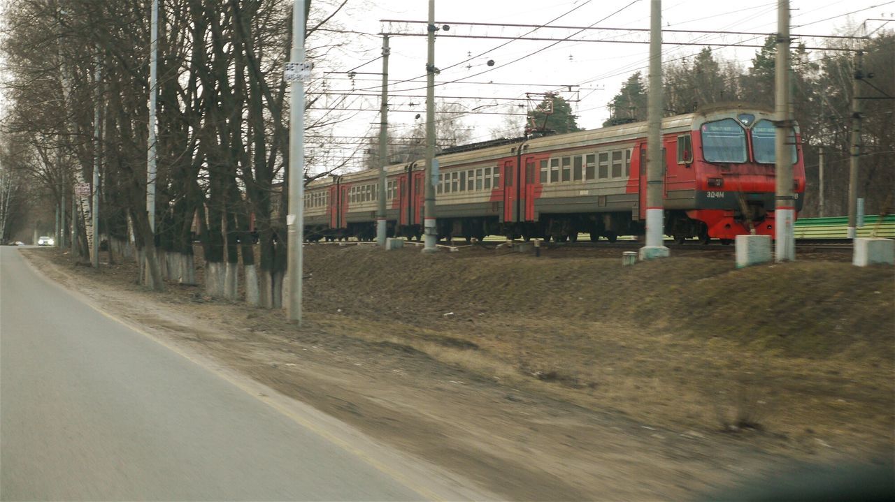 transportation, mode of transport, architecture, building exterior, built structure, road, land vehicle, railroad track, public transportation, car, street, train - vehicle, rail transportation, sky, electricity pylon, travel, train, day, power line, outdoors