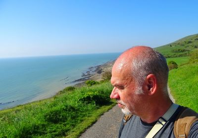 Mature man looking at sea against clear sky during sunny day