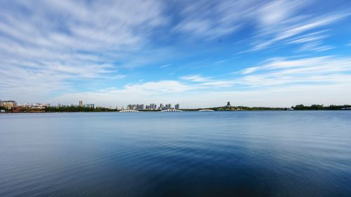 Scenic view of city by sea against sky