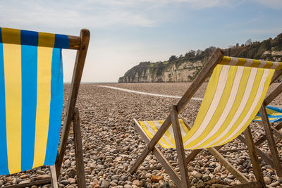 Chairs on beach against sky