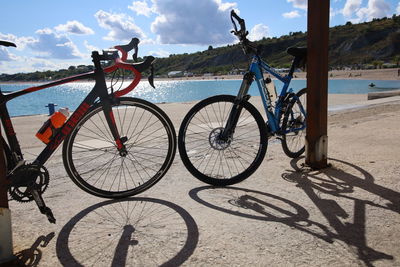 Bicycle parked at beach against sky