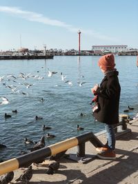 Man on pier at harbor against sky