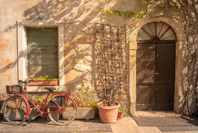 Facade of an old house with a red bicycle and a potted plant