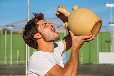 Young man drinking water from container in city