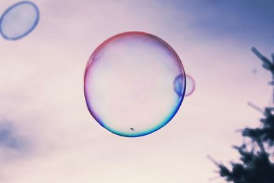 Close-up of bubbles in mid-air against sky