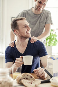 Young gay man massaging partner having breakfast at table