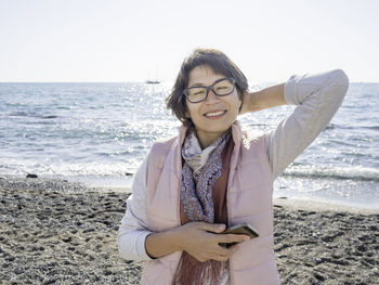 Smiling woman with smartphone on pebble beach.fun on vacation. sincere emotions. sunny day.