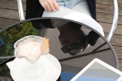 Reflection on the table of a business woman in sunglasses eats,melted ice cream