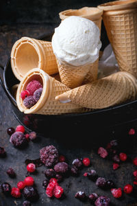 High angle view of ice cream cones by frozen berries on table