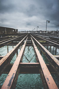 Railroad tracks over sea against cloudy sky