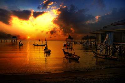 Silhouette boats in sea against sky during sunset