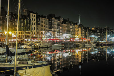 Boats moored at illuminated harbor against sky at night