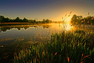 Scenic view of lake against sky at sunset