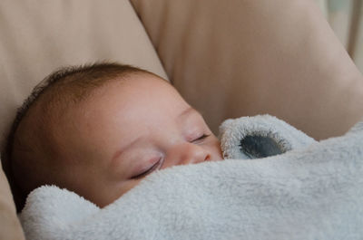 Close-up of toddler baby boy sleeping on bed at home