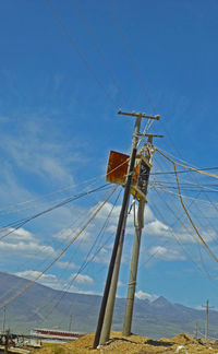 Low angle view of electricity pylon on field against sky