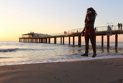 Woman standing on beach against clear sky