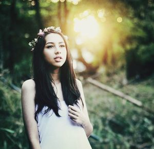 Portrait of beautiful young woman against trees