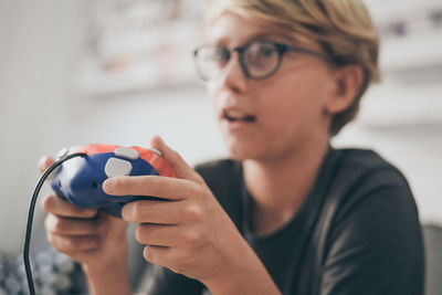 Close-up of cute boy playing video game at home