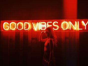 Full length of woman standing on illuminated sign