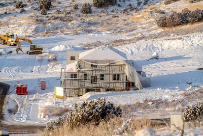 Houses on snow covered field by buildings