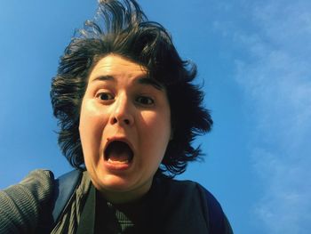 Close-up portrait of boy against blue sky