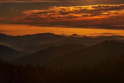 Scenic view of silhouette mountains against orange sky
