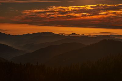 Scenic view of silhouette mountains against orange sky