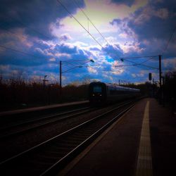 Railroad tracks against cloudy sky