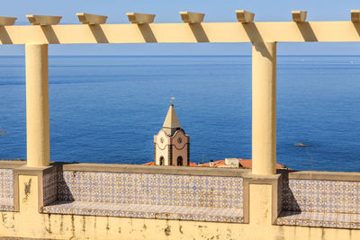 Building by sea against blue sky