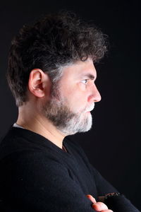 Profile view of serious man with beard against black background