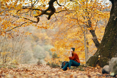 Full length of man sitting on road during autumn