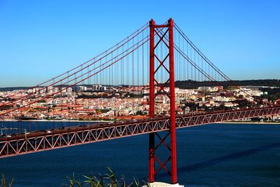 View of red bridge over river with city in background