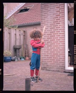 Girl standing outside house against building