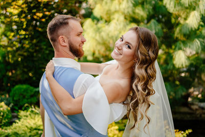 Newlywed couple embracing while standing outdoors