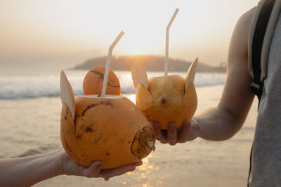 Man and woman drinking fresh coconut water together on idyllic sand beach. 