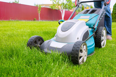 A lawn mower, a close-up. a worker is cutting grass in the backyard on a sunny day