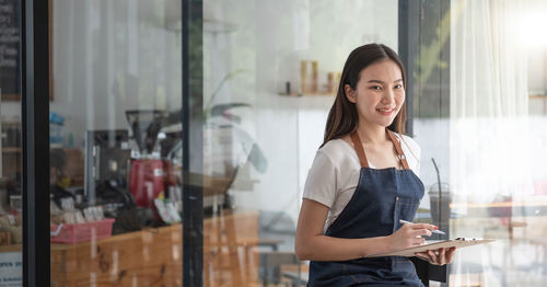 Young woman using phone while standing at home