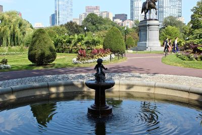 Fountain in park against buildings in city