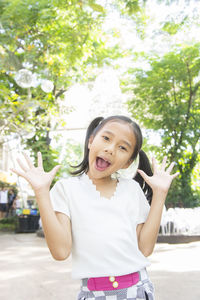 Portrait of cheerful girl standing at public park