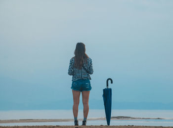 Rear view of woman standing against blue sky