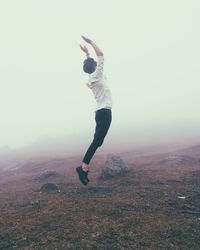 Full length of man jumping on land against sky