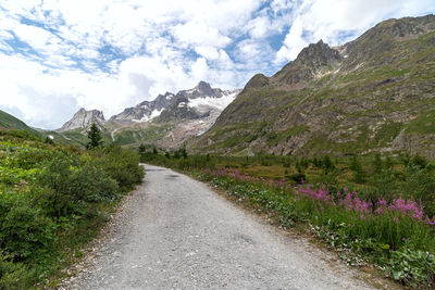 Scenic view of road by mountains against sky