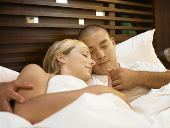 High angle view of couple relaxing on bed at home
