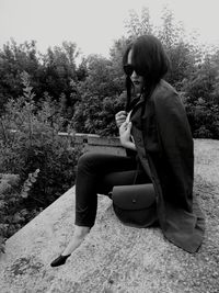 Side view of young woman sitting on tree