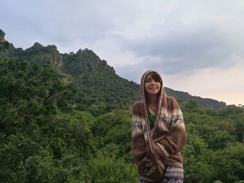 Young woman standing on mountain against sky