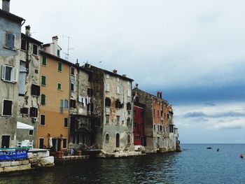 Residential buildings by sea against sky