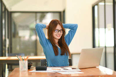 Portrait of young woman using mobile phone in cafe