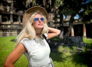 Portrait of young woman standing against trees