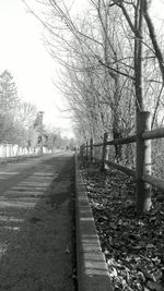 Railroad track amidst bare trees against clear sky